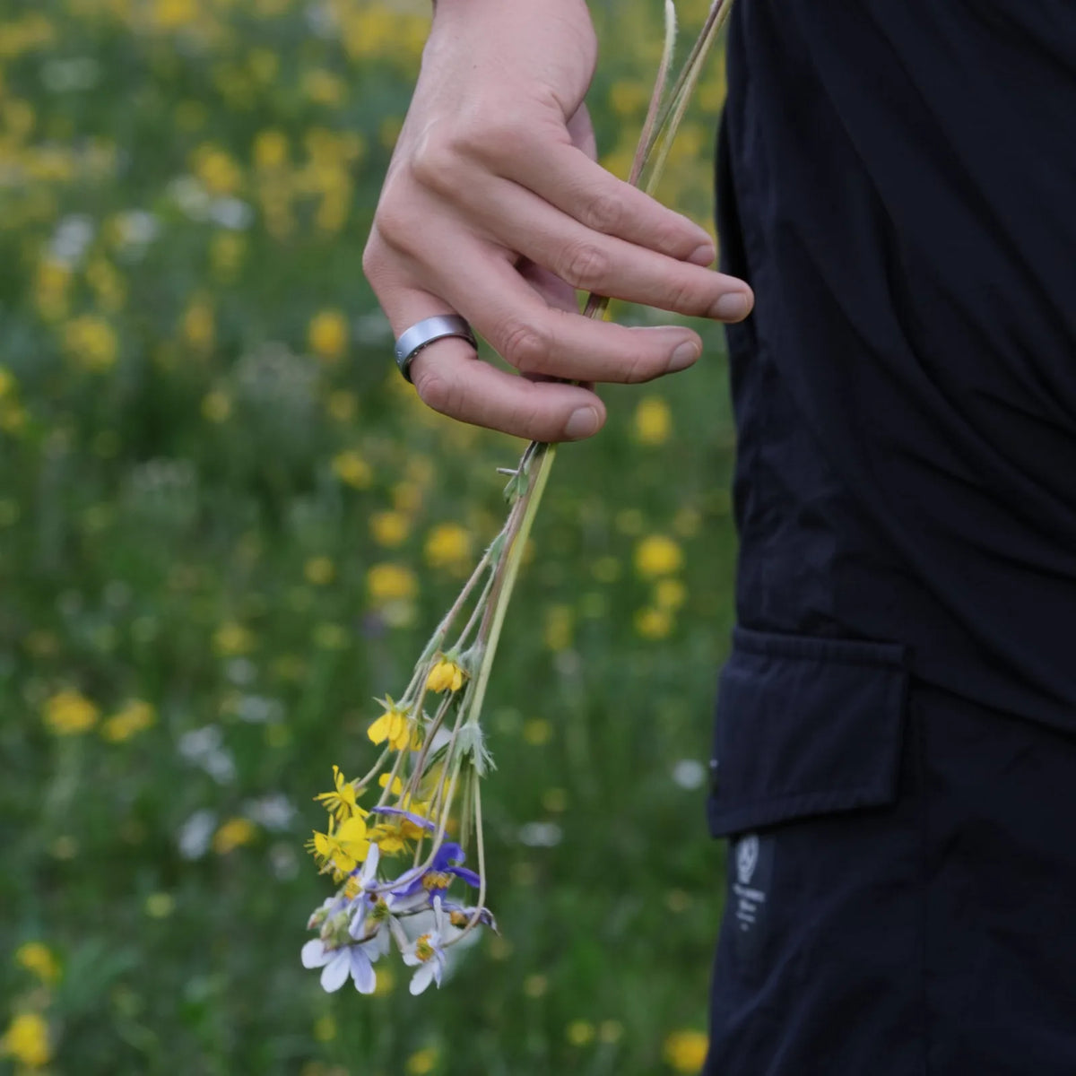 HSRing X3 in brushed silver worn outdoors, holding wildflowers